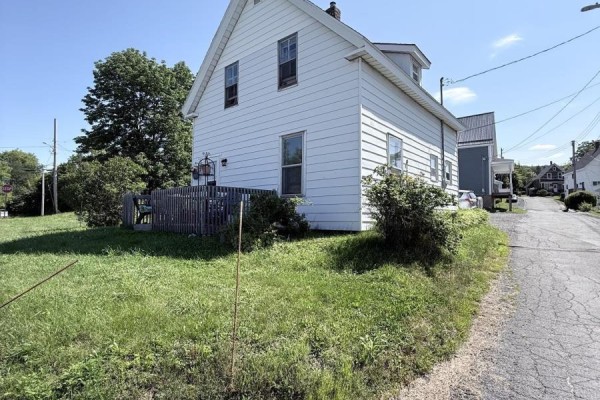Side exterior view of a white house with a wooden fence and grassy yard. - 5 Fraser Lane, Trenton