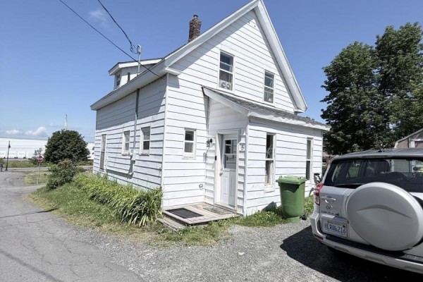 Front exterior view of a white house with a small porch, door, and nearby green bin. - 5 Fraser Lane, Trenton