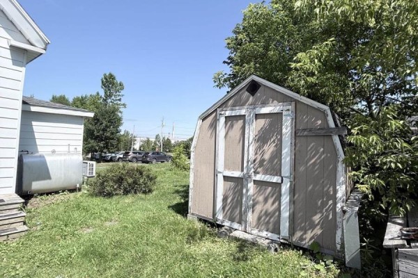 A brown wooden shed sits in a grassy backyard next to a metal oil tank. - 5 Fraser Lane, Trenton