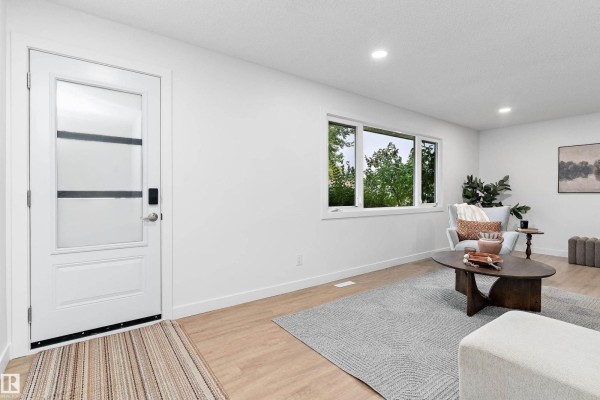 Bright living room with white walls, large window overlooking trees, and light wood flooring. - 5 Glenbrook Bv, Sherwood Park