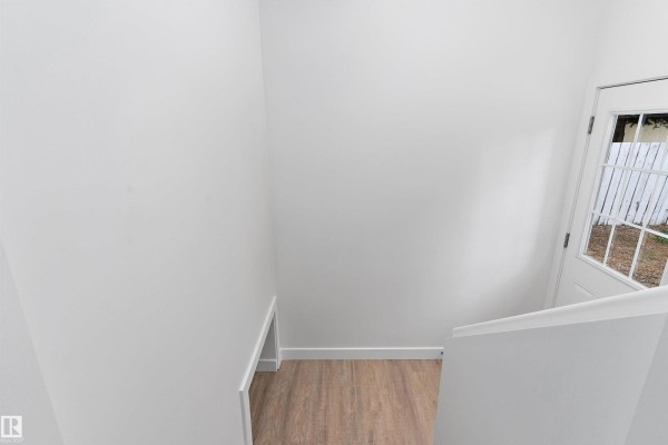 Interior view from a staircase landing, looking down towards a white door and wooden floors. - 5 Glenbrook Bv, Sherwood Park