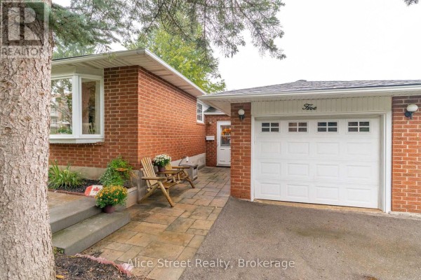 Side view of the red brick bungalow showing a patio with two chairs next to the garage. - 5 Glenbrook Drive, Guelph