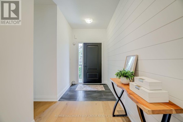 Interior entryway with black front door, shiplap accent wall, console table, and tiled floor. - 5 Harry Thornton Lane, Uxbridge