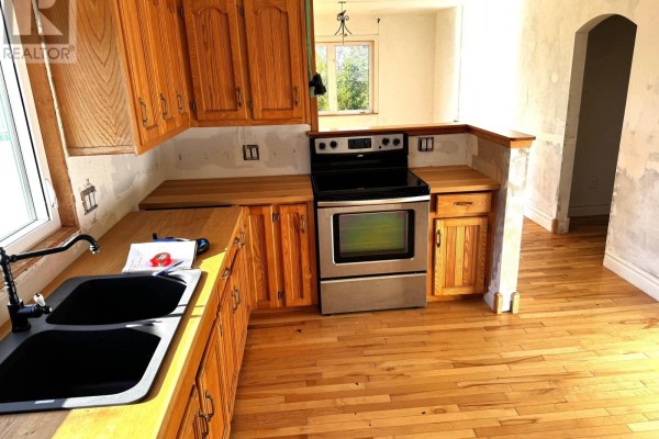 U-shaped kitchen with light wood cabinets, stainless steel stove, black double sink, and hardwood floors. - 5 Homestead Road, Bayswater