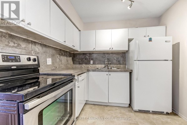 Apartment kitchen with white cabinetry, stainless steel stove, and refrigerator. - 5 Jacksway Crescent, London North