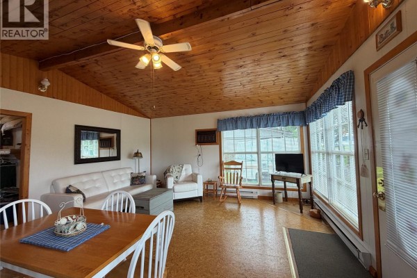 Living and dining area with white sofa, armchair, wooden dining table and chairs, and pine wood ceiling. - 5 Lakeshore Drive, Hudson Bay Rm No  394
