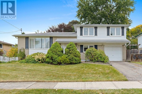 Front view of a two-storey detached house with beige brick and white siding, showing a driveway and lawn. - 5 Lucinda Place, Halton Hills