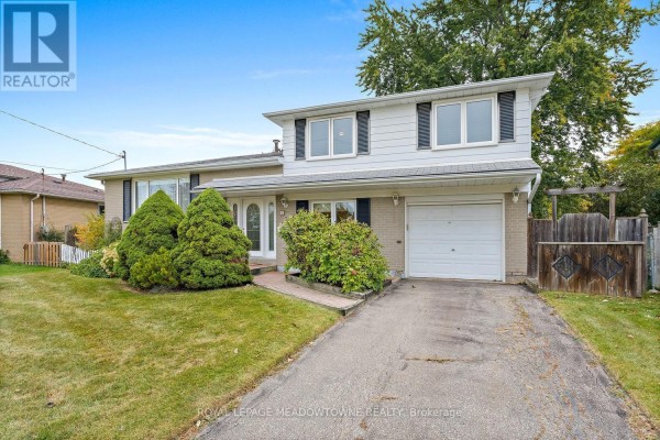 Side angle of a two-storey house with beige brick and white siding, a single garage door, and mature trees. - 5 Lucinda Place, Halton Hills