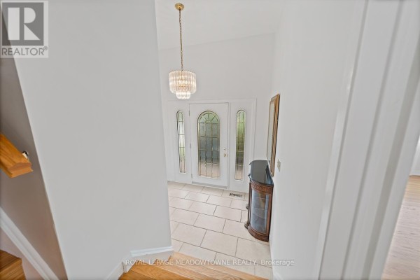 View from the top of the stairs looking down at the tiled foyer with a glass front door and chandelier. - 5 Lucinda Place, Halton Hills