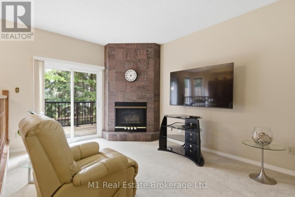 Living and dining room with neutral carpet, two sofas, coffee tables, dining set, and a china cabinet. - 5 Marilyn Drive, Guelph