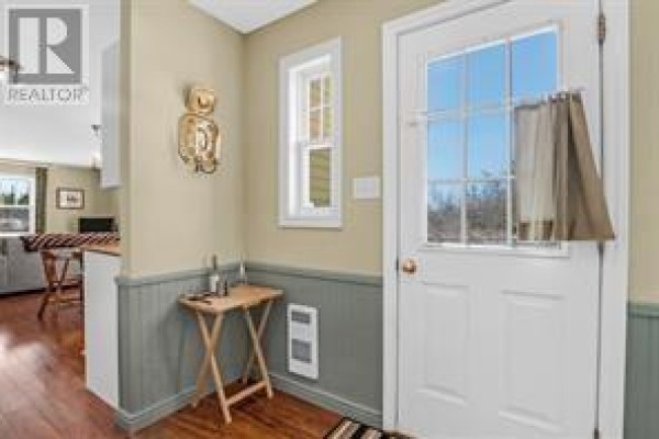 Interior entryway with a white door, small table, and wainscoting. - 5 Marshall’s Hill, Trinity East