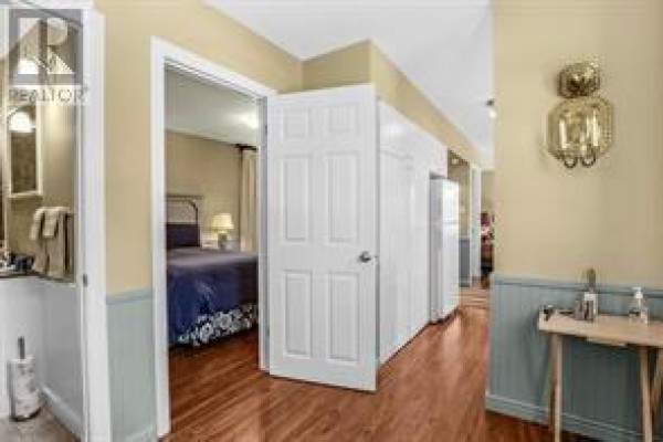 Hallway with white doors, a small table, and entrance to a bedroom. - 5 Marshall’s Hill, Trinity East