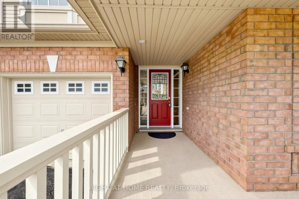 Covered walkway leading to the front door, with a view of the garage door and brick exterior. - 5 Mendoza Drive, Brampton