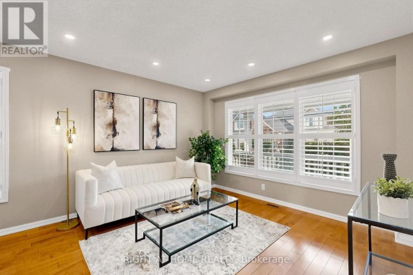 Living room with a white sofa, glass coffee table, floor lamp, and large window with shutters. - 5 Mendoza Drive, Brampton