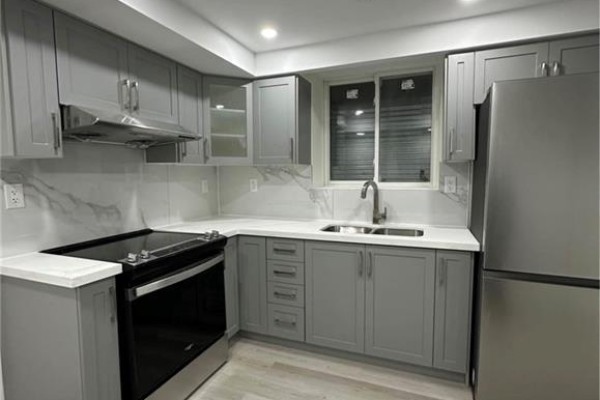 A compact L-shaped kitchen with light grey cabinets, white countertops, and stainless steel appliances. - 5 Munro Circle Unit# Lower, Brantford