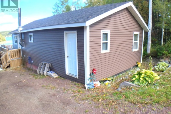 Exterior side of the house with a white door and small garden area. - 5 Old Road, Western Arm Other, Point Leamington