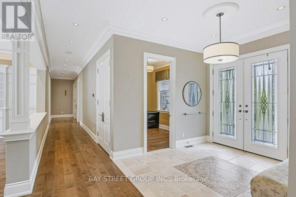 Interior view of a hallway leading from the entryway, featuring wood floors and doors. - 5 River Stone Court, East Gwillimbury