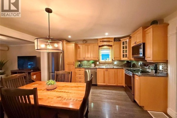 Kitchen and dining area with light wood cabinets, stainless steel appliances, and dark floors. - 5 Saint-joseph Street, Sainte Anne De Madawaska