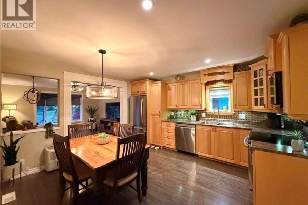 View of the kitchen, dining area, and living room with wood cabinets and furniture. - 5 Saint-joseph Street, Sainte Anne De Madawaska
