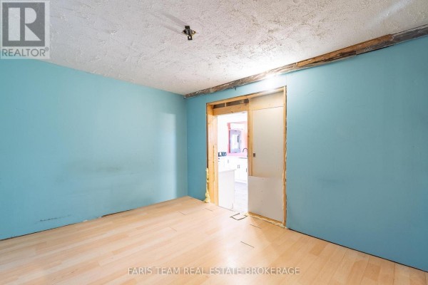 Room with light blue walls, exposed wooden beams, and a doorway leading to a bathroom. - 5 Scott Street, Penetanguishene