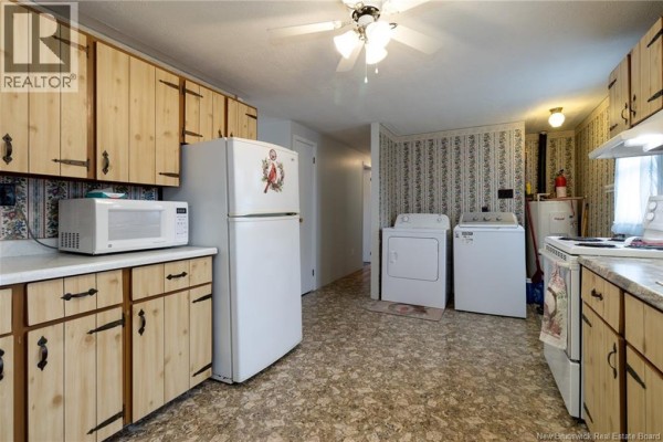 Kitchen with light wood cabinets, a sink, stove, refrigerator, and view into dining room. - 5 Sewell Road, Jacksonville