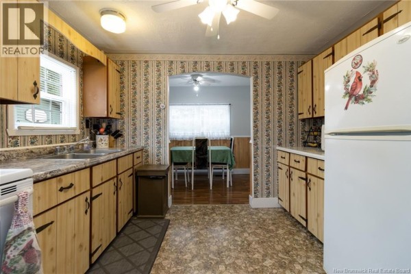 Kitchen with white appliances including a stove and laundry machines, light wood cabinets, and a door. - 5 Sewell Road, Jacksonville