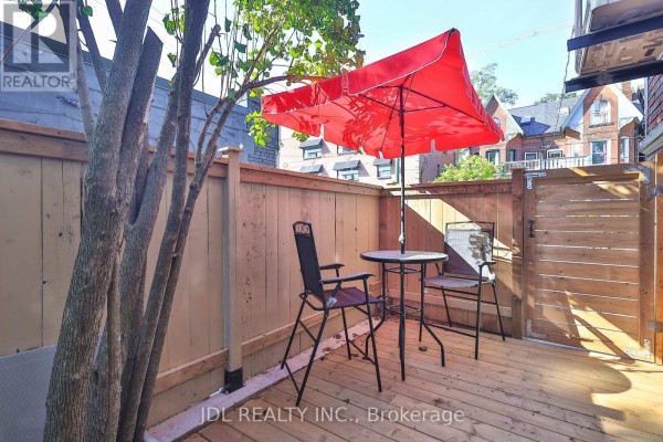 Red patio umbrella over a round table with chairs on a wooden deck. - 5 Sorauren Avenue, Toronto