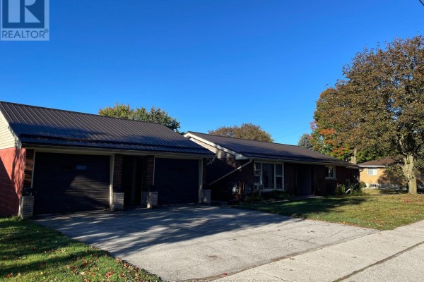 Attached garage with two dark brown doors next to a brick house with a dark metal roof. - 5 Stinson Street, South Bruce