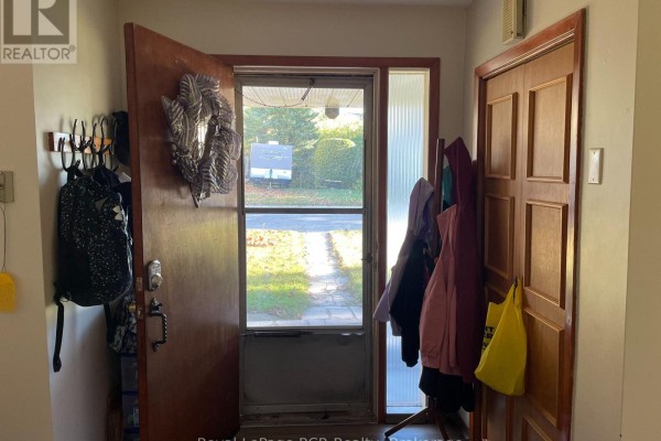 Entryway with a screen door looking out to a driveway, coat rack, and wooden door. - 5 Stinson Street, South Bruce