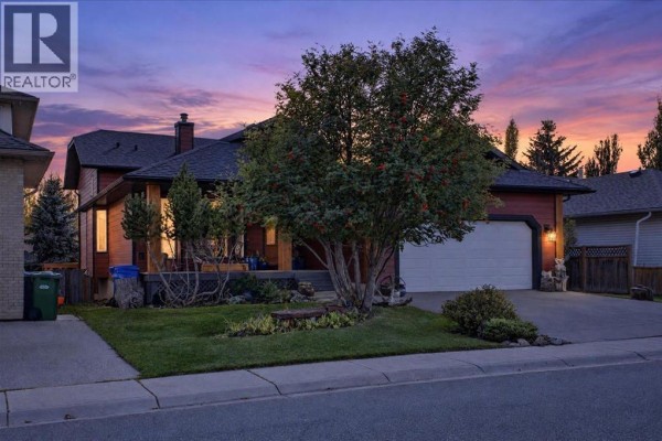 Front exterior of a residential house with a double garage door and wood trim. - 5 Sunset Crescent, Okotoks