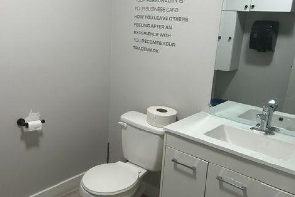 Small washroom with white toilet, sink vanity, mirror, and inspirational quote on the wall. - 5 To 8 - 112 Saunders Road, Barrie