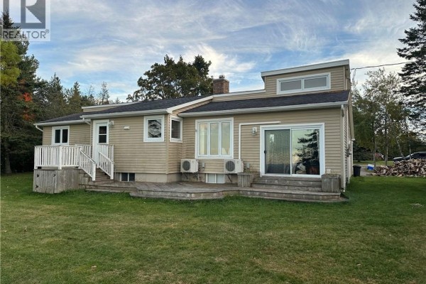 Rear view of the beige bungalow showcasing a large wooden deck with access to the interior. - 5 Valleyview Drive, Wards Creek