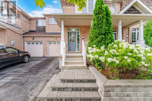 Close-up exterior view of a townhouse unit with a driveway, garage, and landscaped front yard. - 5 Westhampton Way, Hamilton