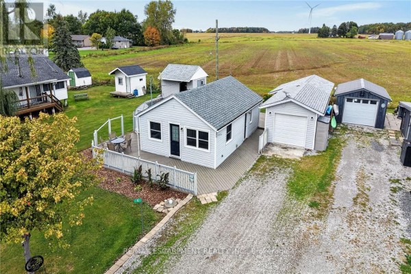 Elevated aerial view of a grey bungalow, garage, and outbuildings on a gravel driveway. - 5 Willoway Lane, Haldimand