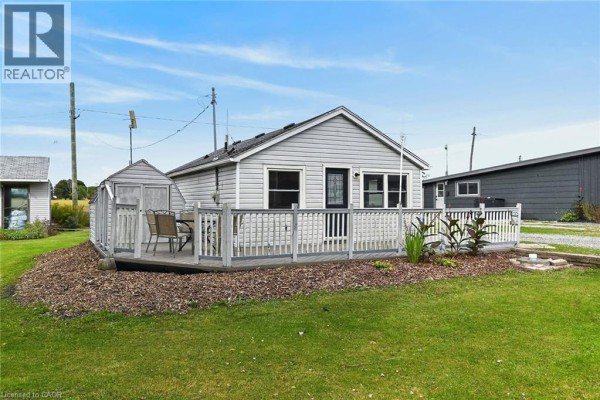 Rear exterior view of the bungalow showing the grey deck with outdoor seating and surrounding green lawn. - 5 Willoway Lane, Selkirk