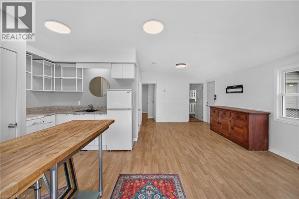 Interior view of an open-concept living space with a kitchen area featuring white cabinets and a wooden island. - 5 Willoway Lane, Selkirk