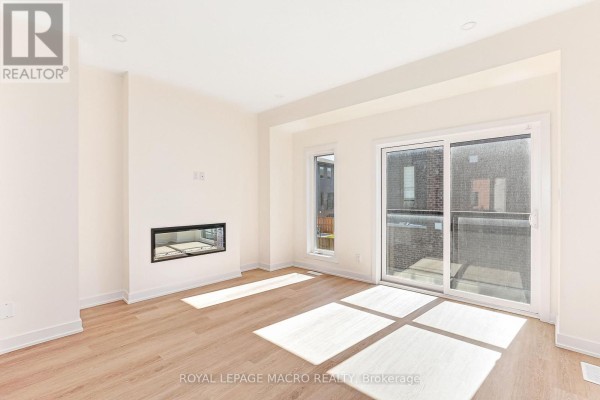 Living room with light wood floors, white walls, glass sliding doors, and a modern fireplace. - 5 Winters Crescent Nw, Collingwood