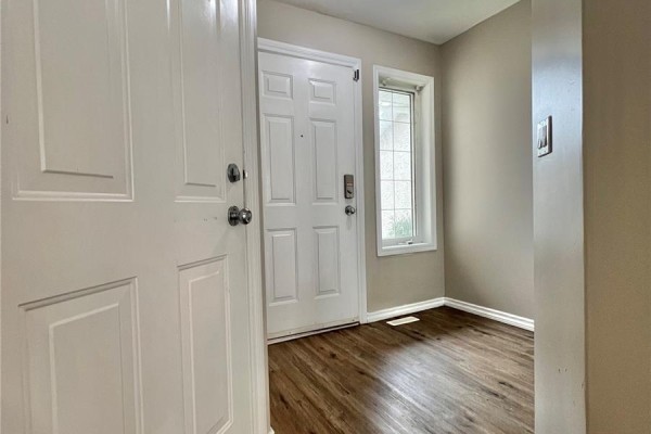 Hallway view showing entrance to living area, stairs to upper level, and white doors. - 50 103 Banyan Crescent, Saskatoon