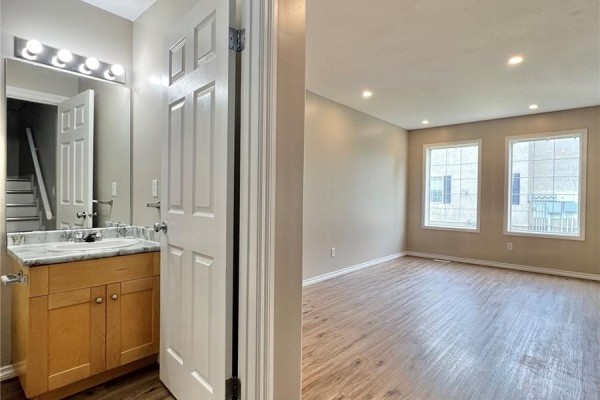 Open-concept living area with wood-look floors, two windows, sliding glass door, and wood counter. - 50 103 Banyan Crescent, Saskatoon