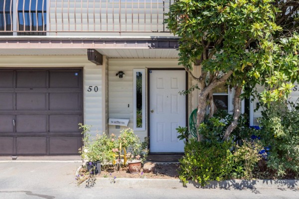 Front entrance of a townhouse with a white door, adjacent to a brown garage door. - 50 27272 32 Avenue, Langley