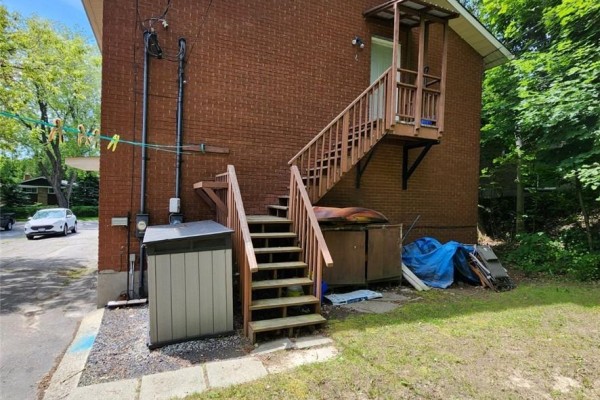 Side view of a brick building with an external wooden staircase and storage shed. - 50 Albany Street, Sudbury