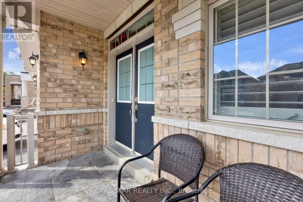Close-up of the front porch with a dark blue double door, brick facade, and chairs. - 50 Brookwater Crescent, Caledon
