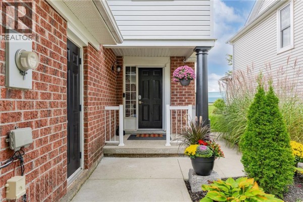 Interior entryway with a carpeted staircase, tiled floor, and a white door. - 50 Calvin Court, Cambridge