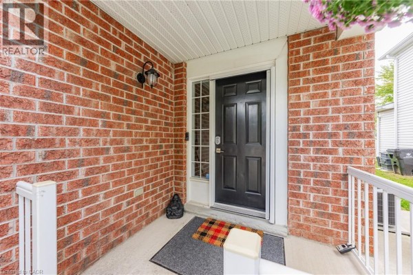 Entryway with a white door, tiled floor, striped rug, and wall decor. - 50 Calvin Court, Cambridge