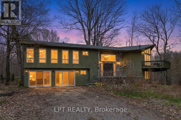 Aerial view of a wooded property with a river and distant agricultural fields. - 50 Concession Rd 2 W, Tiny