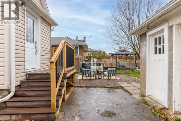 Backyard view showing stairs to the house, a patio area with seating, and a detached garage. - 50 Fifth Street, Welland