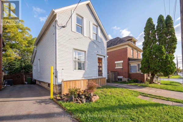 Side exterior view of a two-story light grey wood-sided house with a driveway and grass lawn. - 50 Flora Street, St  Thomas