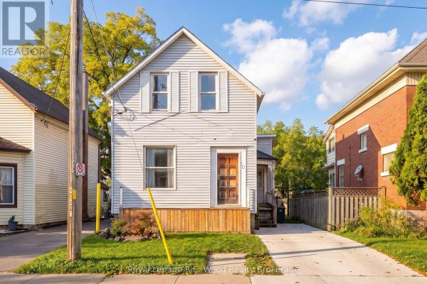 Front view of the light grey two-story house with a porch and driveway on a sunny day. - 50 Flora Street, St  Thomas