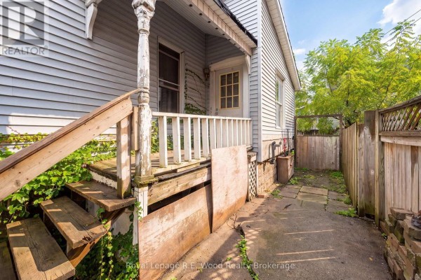 Side view of the house showing a wooden porch with stairs and a stone pathway. - 50 Flora Street, St  Thomas