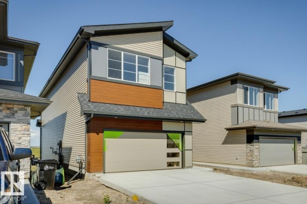 Open-concept kitchen with white cabinets, quartz island, and dark grey backsplash tiles. - 50 Gambel Lo, Spruce Grove
